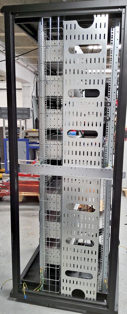 19-inch bay structure before wiring: uprights, blanking plates and vertical wire cable trays.